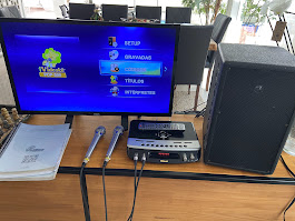 Menu do aparelho de Videokê exibido na TV com caixa de som ao lado